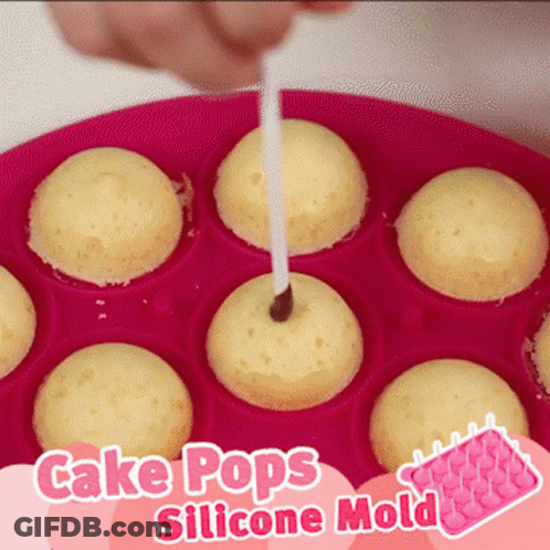 A Pink Cake Pops Silicone Mold With A Person Sticking A Stick In It GIF