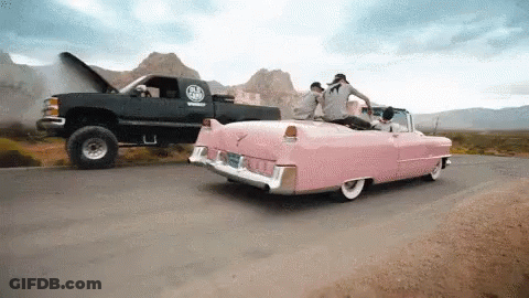 A Pink Car Is Being Towed By A Black Truck With The Hood Up GIF
