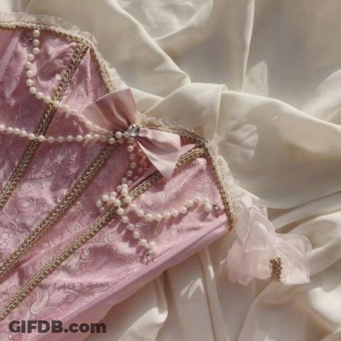 A Pink Corset With Pearls And A Bow On It GIF