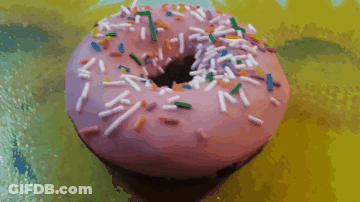 A Pink Donut With Sprinkles On It On A Yellow Surface GIF