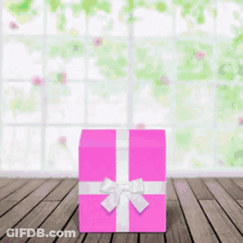A Pink Gift Box With A White Bow Is Sitting On A Wooden Floor GIF