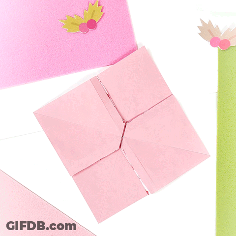 A Pink Origami Bird With Leaves On It Is Sitting On A Table GIF