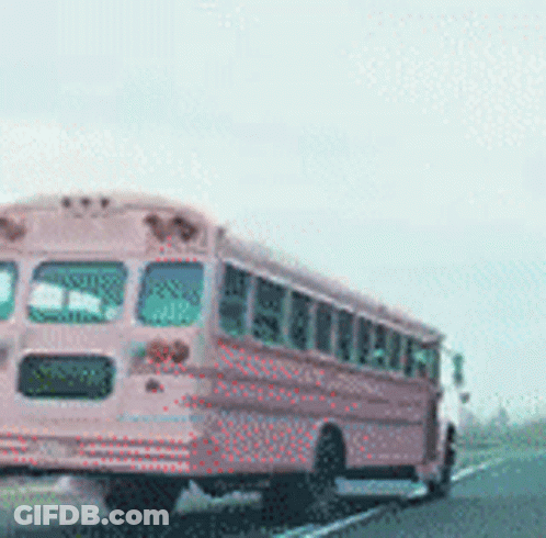 A Pink School Bus Drives Down A Highway GIF