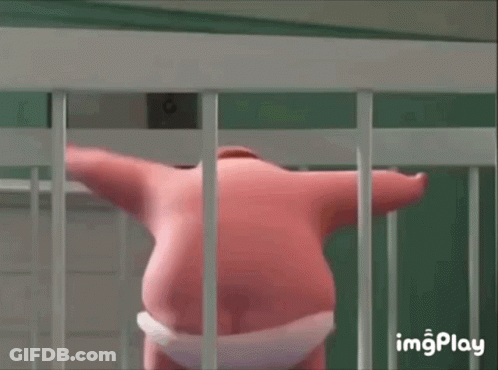 A Pink Stuffed Animal Is Standing In A Cage Behind Bars . GIF
