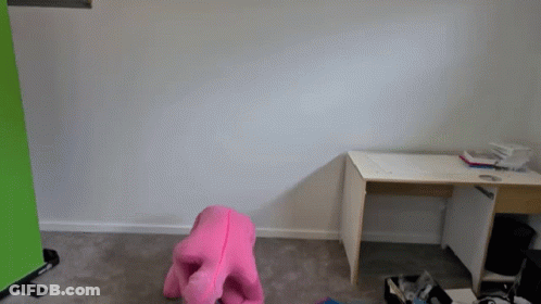 A Pink Stuffed Animal Sits In Front Of A Desk In An Empty Room GIF