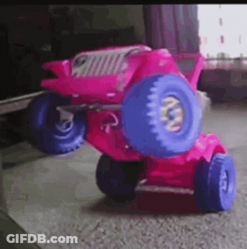 A Pink Toy Jeep With Blue Wheels Is Sitting On A Carpet . GIF