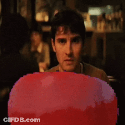 A Pixelated Image Of A Man Sitting In Front Of A Red Object GIF