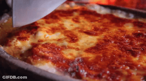 A Pizza With A Lot Of Cheese And Sauce Is Being Scooped Out Of A Pan With A Spatula . GIF