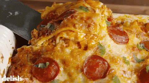 A Pizza With Pepperoni And Cheese Is Being Scooped Out Of A Casserole Dish By A Spatula .. GIF