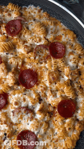 A Pizza With Pepperoni And Macaroni And Cheese In A Pan GIF
