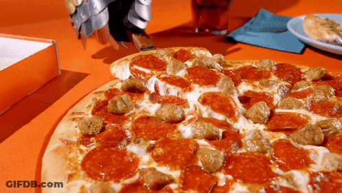 A Pizza With Pepperoni And Sausage Is Sitting On A Table GIF