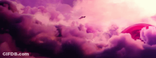 A Plane Flying Through A Cloudy Sky With A Red Object In The Background GIF
