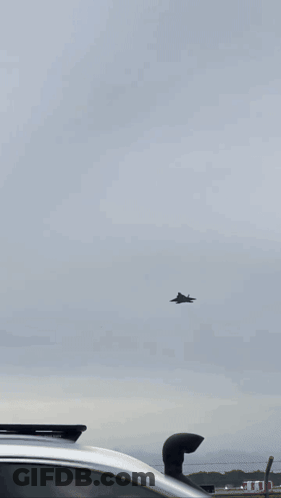 A Plane Is Flying Through A Cloudy Sky . GIF