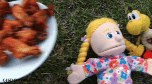 A Plate Of Chicken Wings Sits Next To A Puppet GIF