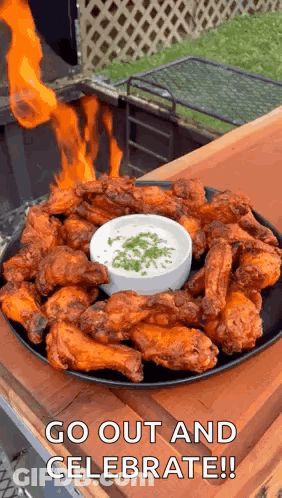 A Plate Of Chicken Wings With A Dipping Sauce And Fire Coming Out Of Them . GIF
