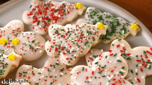 A Plate Of Christmas Cookies With Icing And Sprinkles And The Word Delish On The Bottom GIF