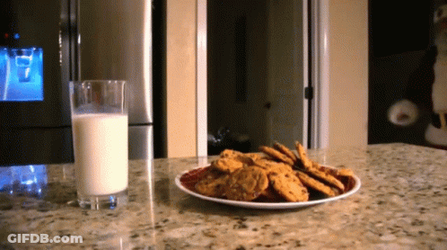A Plate Of Cookies Next To A Glass Of Milk On A Counter GIF