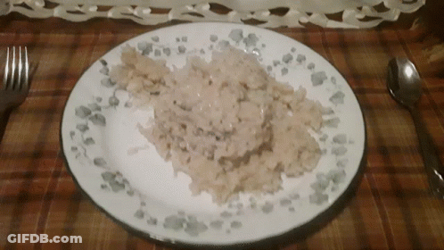 A Plate Of Food With A Spoon And Fork On A Table GIF