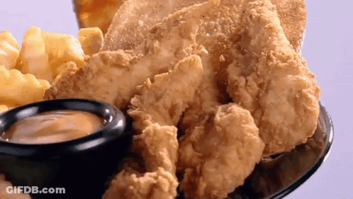 A Plate Of Fried Chicken And French Fries With A Small Bowl Of Dipping Sauce GIF