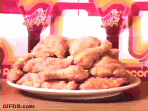 A Plate Of Fried Chicken Sits On A Table In Front Of A Wendy 'S Sign GIF