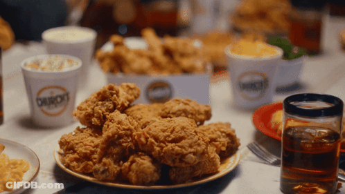 A Plate Of Fried Chicken Sits On A Table Next To A Cup That Says Bourbon 'S GIF