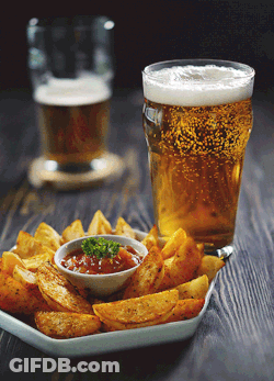 A Plate Of Fries And A Glass Of Beer On A Wooden Table GIF