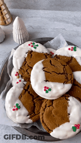 A Plate Of Gingerbread Cookies With White Frosting And Holly On Them GIF