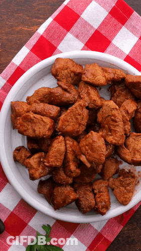A Plate Of Meat On A Checkered Tablecloth GIF