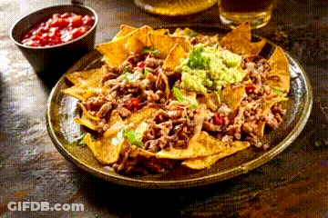 A Plate Of Nachos With Guacamole And Salsa Next To A Bowl Of Salsa On A Table . GIF