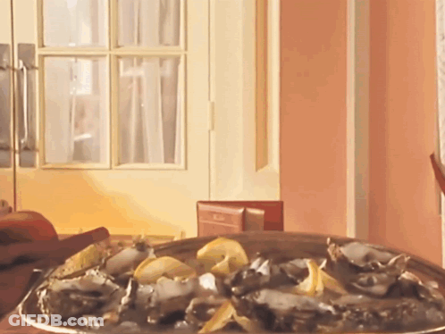 A Plate Of Oysters Sits On A Table In Front Of A Pink Wall GIF
