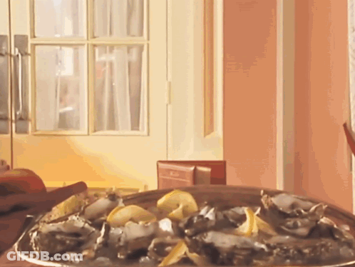 A Plate Of Oysters Sits On A Table In Front Of A Pink Wall GIF