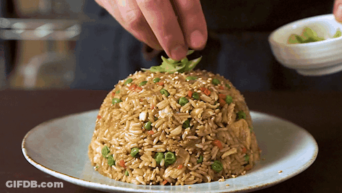 A Plate Of Rice With Vegetables And Sesame Seeds On It GIF