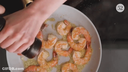 A Plate Of Shrimp Is Being Sprinkled With Salt And Pepper GIF