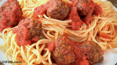 A Plate Of Spaghetti And Meatballs Covered In Sauce GIF