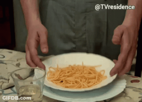 A Plate Of Spaghetti Is On A Table With A Glass Of Wine GIF