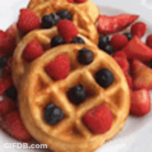 A Plate Of Waffles With Strawberries And Blueberries On It . GIF