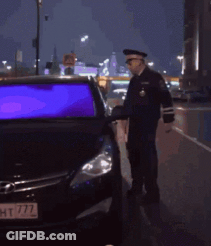 A Police Officer Checks A Car 'S Rear View Mirror GIF