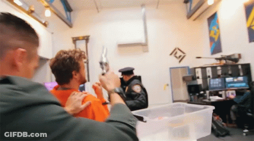 A Police Officer Holds A Gun Over A Man 'S Head GIF