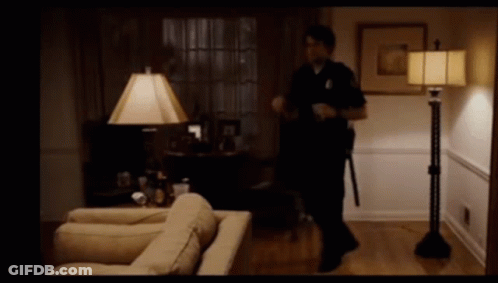 A Police Officer In A Living Room With A Lamp GIF
