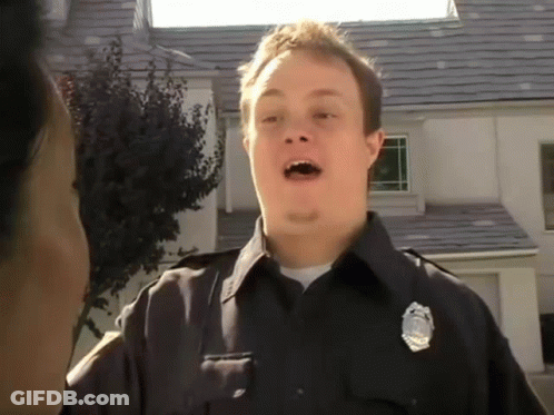 A Police Officer In Front Of A House With A Badge On His Chest GIF