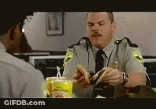 A Police Officer Is Eating A Hamburger In A Restaurant GIF