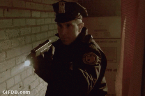 Police Officer Holding Gun In Front Of Wall GIF