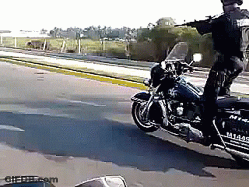 A Police Officer Is Riding A Harley Davidson Motorcycle On The Street GIF