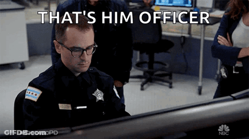 A Police Officer Is Sitting In Front Of A Computer With The Words That 'S Him Officer Above Him GIF