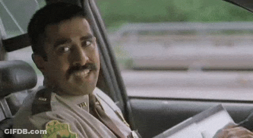 A Police Officer Is Sitting In The Driver 'S Seat Of A Car Holding A Piece Of Paper . GIF