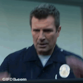 A Police Officer Is Standing In Front Of A Window And Looking Out . GIF