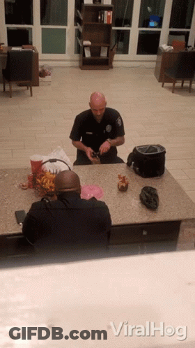 A Police Officer Sits At A Counter With Another Officer GIF