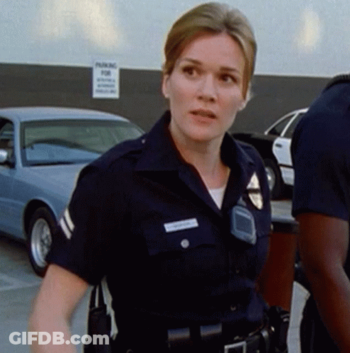 A Police Officer Stands In Front Of A Sign That Says Parking GIF