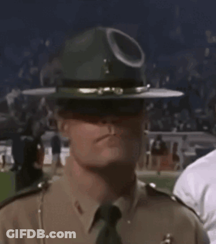 A Police Officer Wearing A Hat And Sunglasses Is Standing In A Crowd . GIF