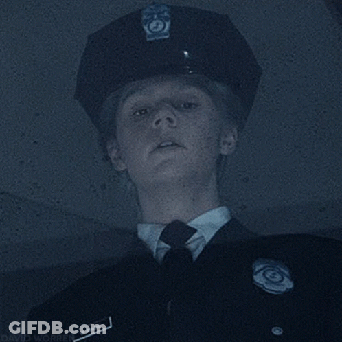 A Police Officer Wearing A Hat And Tie Is Looking Up At Something . GIF